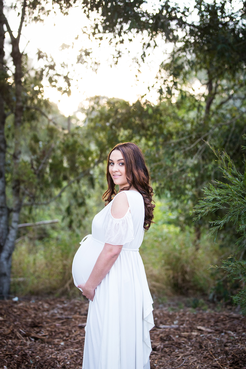 pregnant girl in white dress in front yellow flowers